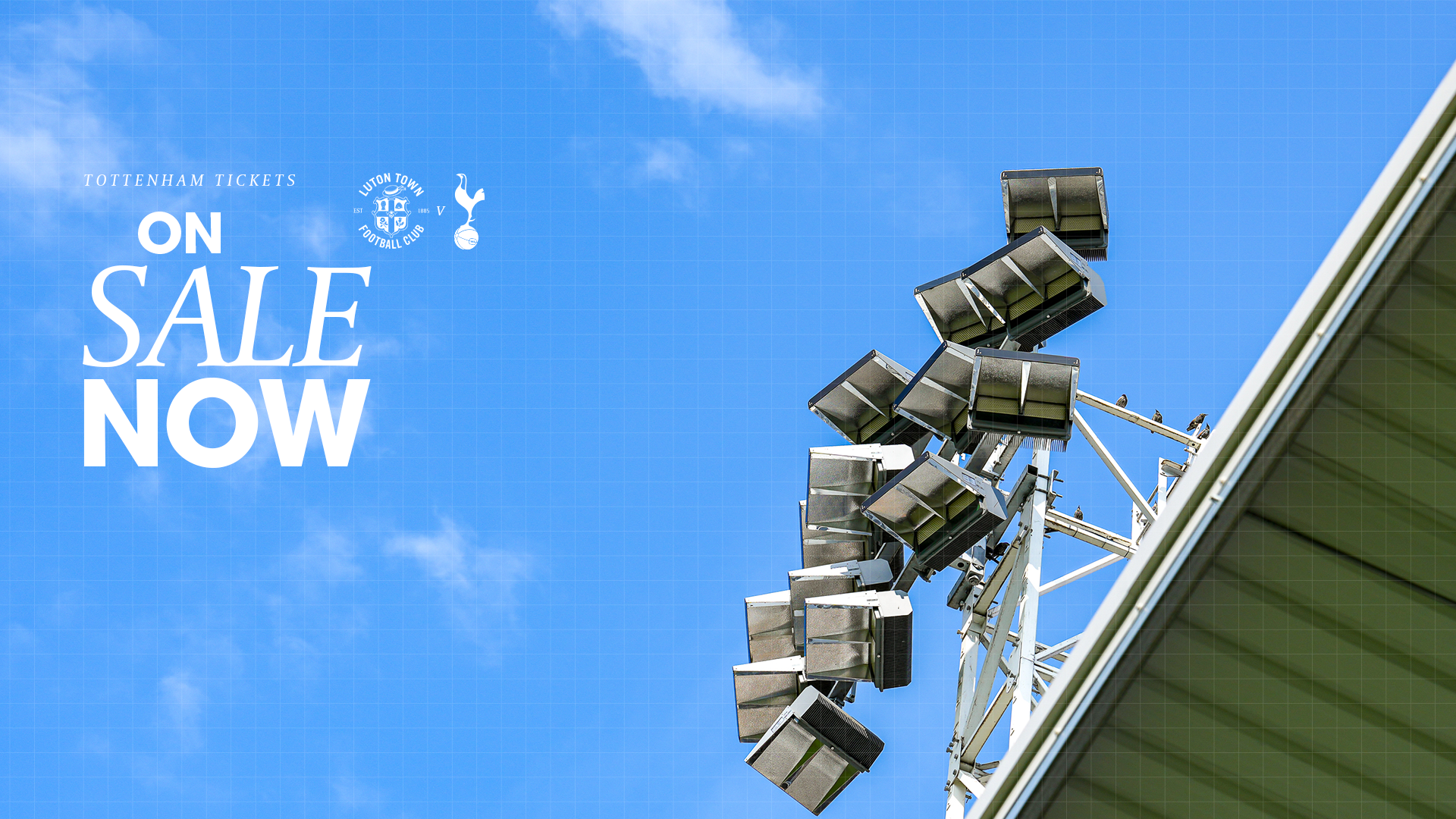 A graphic showing that Spurs tickets are on sale now, against a backdrop of blue sky over a floodlight pylon above the Bobbers Stand at Kenilworth Road.