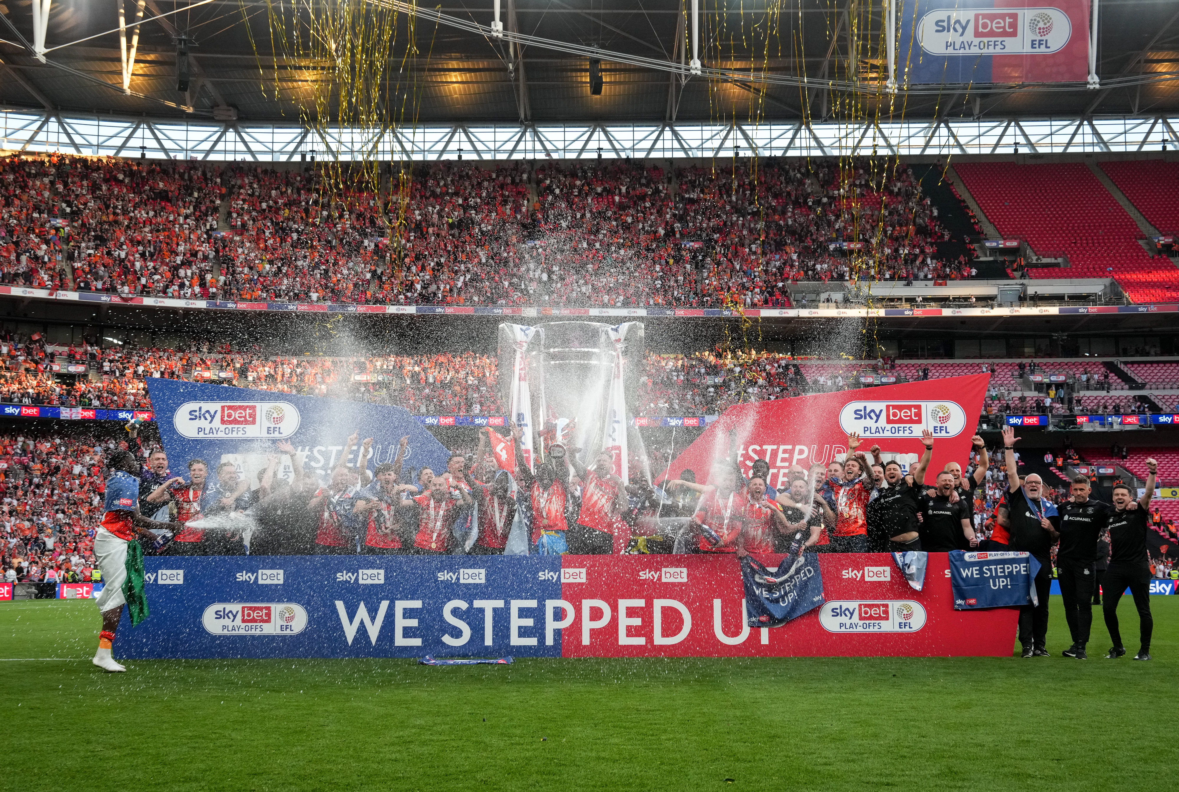 The victorious Luton Town team celebrate on the pitch at Wembley at the end of the Championship play-off final in 2023.
