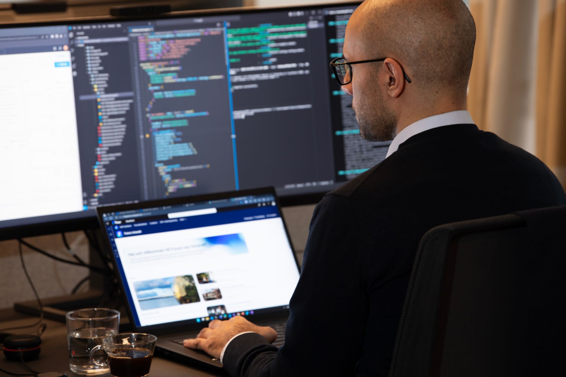 Man med glasögon arbetar vid dator i ett kontorsmiljö.