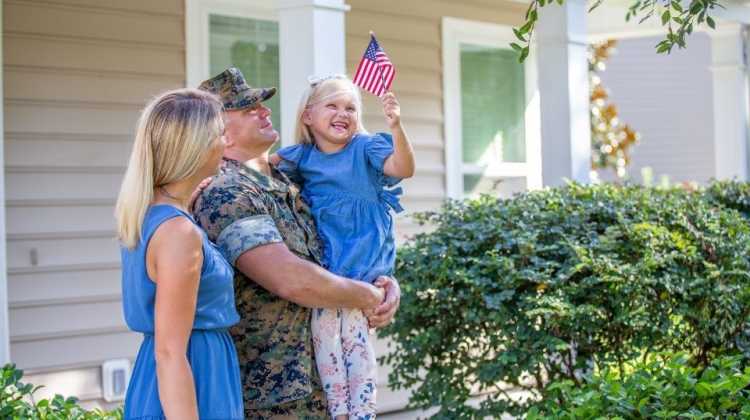 military couple and child holding a small flag, after deciding the pros and cons of renting vs. buying a home