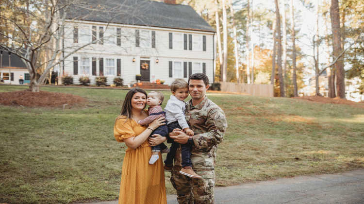military family selling a home standing in the front yard