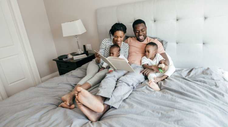 family reading together in hotel bed, looking for short-term rental solutions during a PCS move