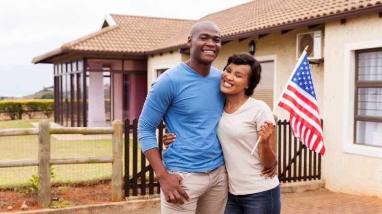 couple holding flag in front of home