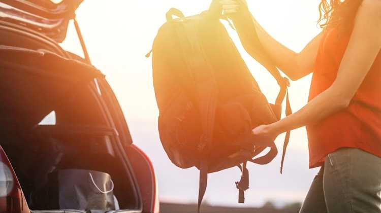 woman taking backpack out of trunk