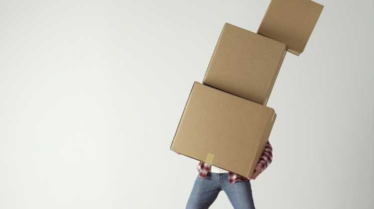 person carrying a stack of boxes during a horrible PCS move with the worst moving company