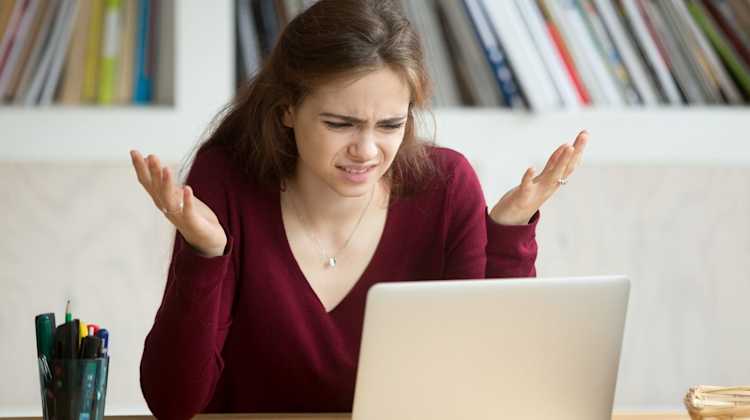 woman looking at laptop in confusion