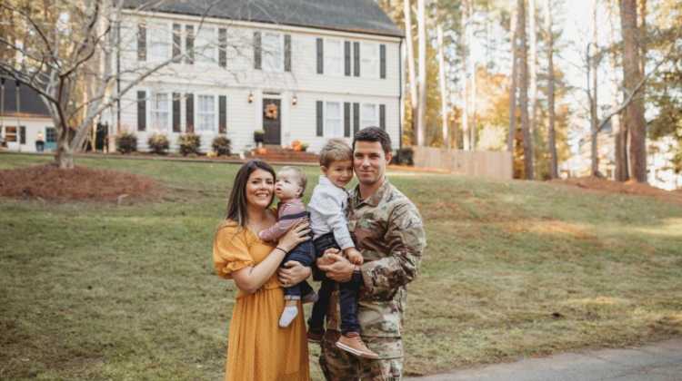 Military Retiree Pay, veteran couple stands in front of new home, after buying a home after military retirement