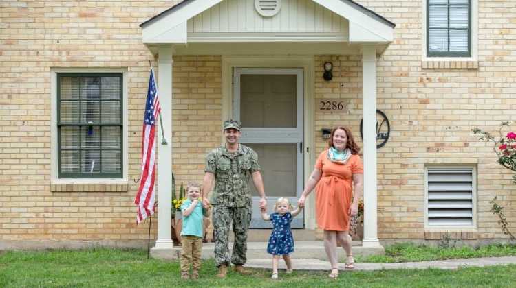 military family standing in front of home