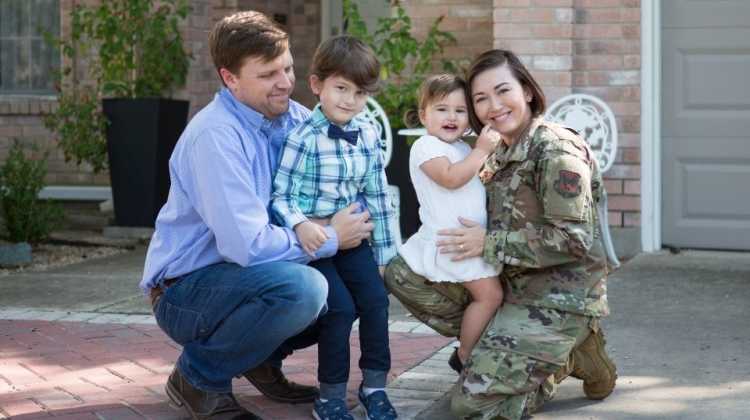 Military family posing in front of home