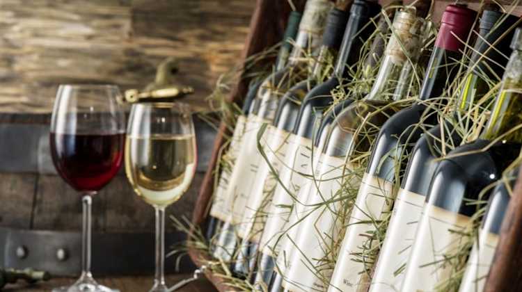 Italian wine bottles packed in a crate, next to glasses of red and white wine, for service members transporting alcohol from Italy to the US