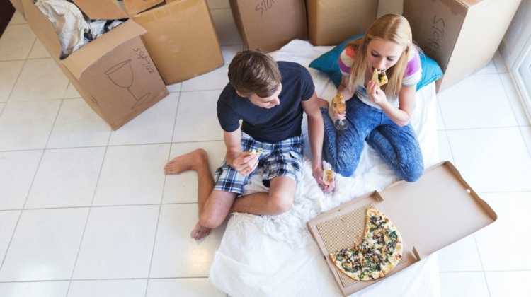 young military couple eating pizza for lunch on moving day