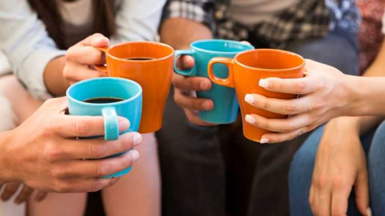 4 friends hold coffee mugs together, after meeting new people after a winter PCS move
