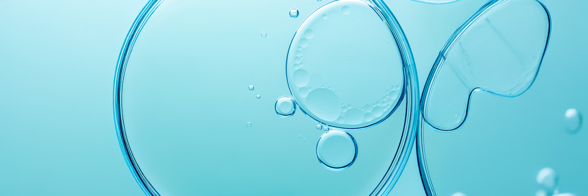 Abstrakter türkisfarbener Hintergrund mit transluzenten, kugelförmigen Blasen, die auf aktive Inhaltsstoffe hindeuten.