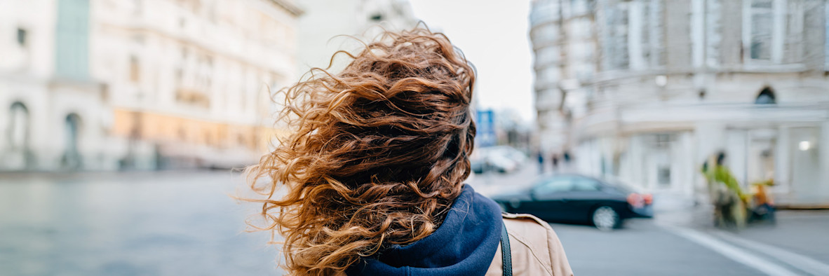 Nahaufnahme von langem, welligem braunem Haar mit lockiger Struktur, das reichhaltige Textur und Volumen zeigt.