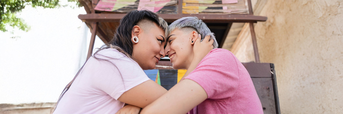 Ein Paar hält sich eng umschlungen vor einem lebendigen, farbenfrohen Hintergrund.