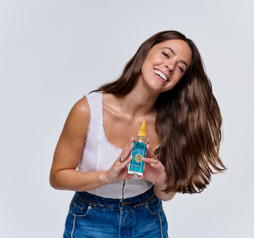 Frau hält Head & Shoulders DERMAX Pro Serum und lacht.