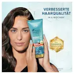 Frau hält eine Flasche Haarpflegeprodukt in der Hand und blickt in die Kamera.