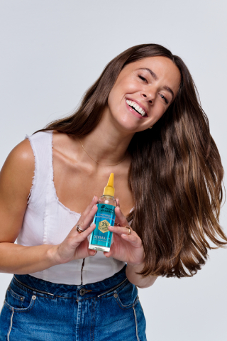 Frau hält Head & Shoulders DERMAX Pro Serum und lacht.