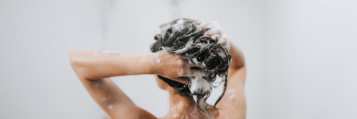 Eine Frau massiert Shampoo in ihr Haar ein.
