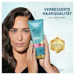 Frau hält Head & Shoulders DermaX Pro Verpackung vor sechseckigem Hintergrund.