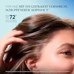 Frau mit glänzendem Haar berührt ihre Kopfhaut, Text: „Mit Feuchtigkeit versorgte, schuppenfreie Kopfhaut“.
