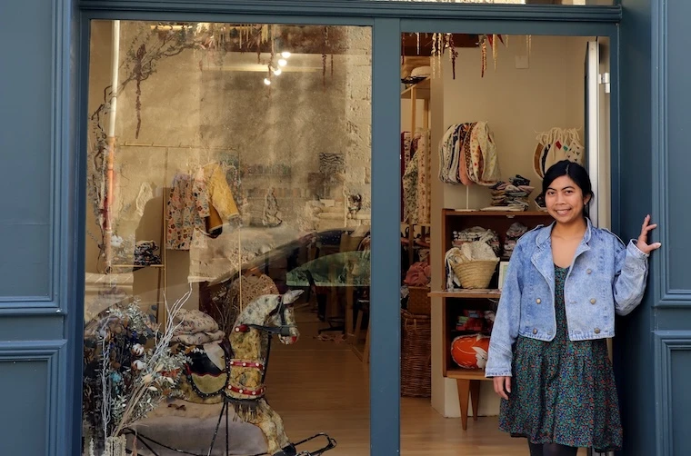 Entrepreneuse financée par l'Adie dans l'embrasure de la porte de sa boutique