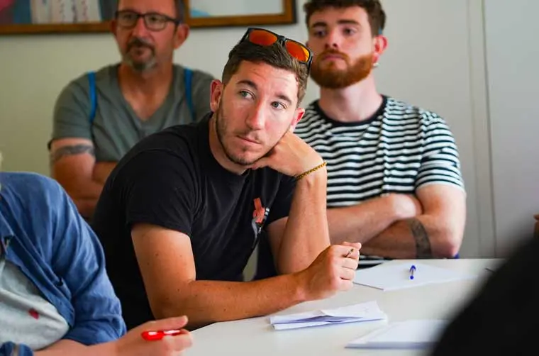 Jeune entrepreneur financé par l'Adie écoutant et prenant des notes