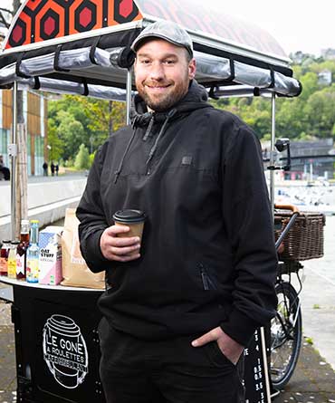 Adrien, 35 ans, originaire de Toulouse, lance en mars 2024 "Le Gone à Roulettes", un café ambulant écoresponsable à Lyon. Après des expériences variées à l'étranger et un CAP cuisine, il obtient des financements de l'Adie et de la Chambre de commerce pour réaliser son projet. Malgré quelques défis initiaux, il connaît un succès grandissant grâce à sa détermination et à ses produits artisanaux.