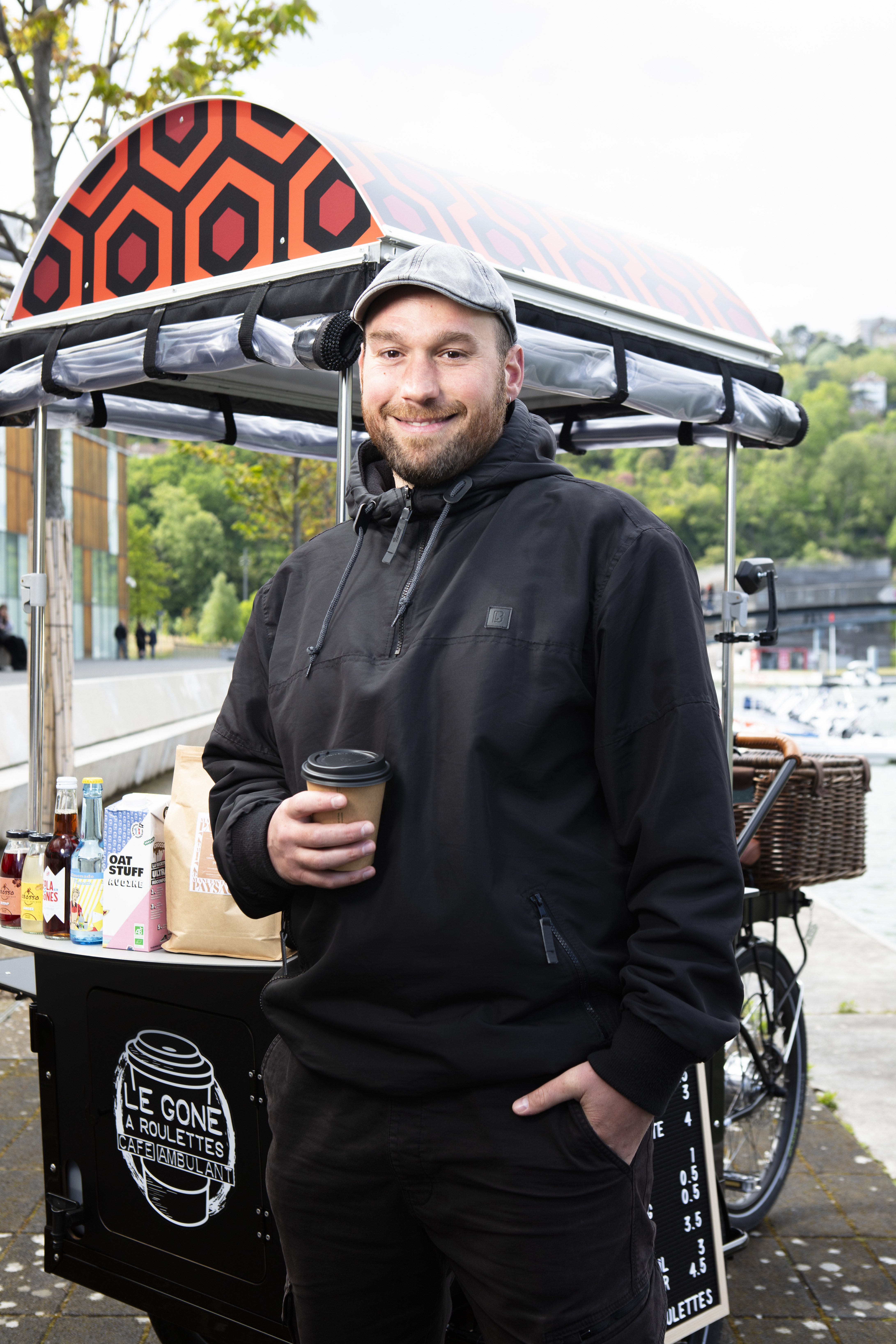 Adrien, 35 ans, originaire de Toulouse, lance en mars 2024 "Le Gone à Roulettes", un café ambulant écoresponsable à Lyon. Après des expériences variées à l'étranger et un CAP cuisine, il obtient des financements de l'Adie et de la Chambre de commerce pour réaliser son projet. Malgré quelques défis initiaux, il connaît un succès grandissant grâce à sa détermination et à ses produits artisanaux.