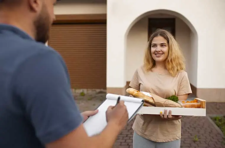 Entrepreneuse financée par l'Adie apportant sa livraison de courses à domicile