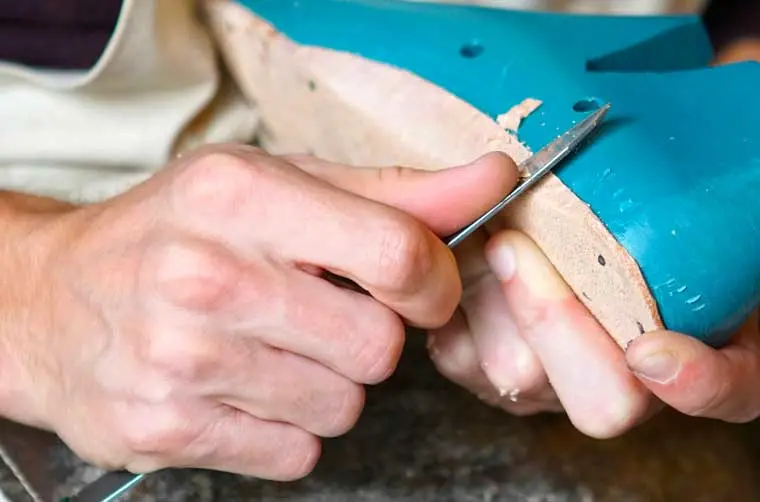 Cordonnier financé par l'Adie travaillant une semelle 