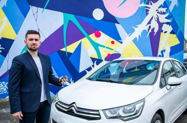 Entrepreneur financé par l'Adie debout devant son véhicule professionnel. 