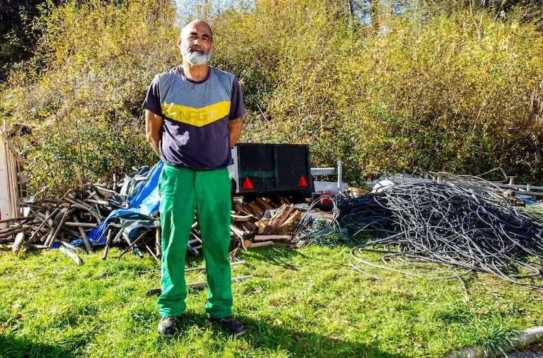 Entrepreneur financé par l'Adie debout devant son tas de ferrailles