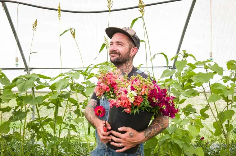 Entrepreneur ayant un statut de Cape financé par l'Adie tenant un pot rempli de fleurs