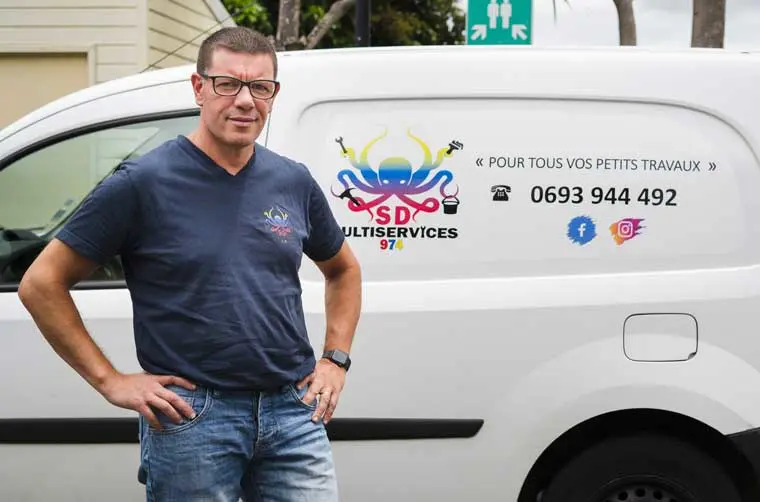 Homme toute main financé par l'Adie devant son véhicule professionnel