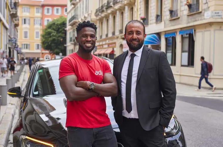 Chauffeur VTC avec son conseiller Adie devant son véhicule professionnel