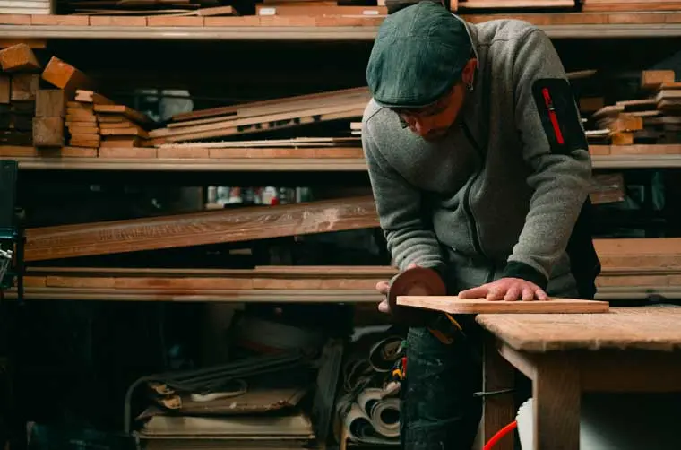 Entrepreneur financé par l'Adie ponçant une planche de bois