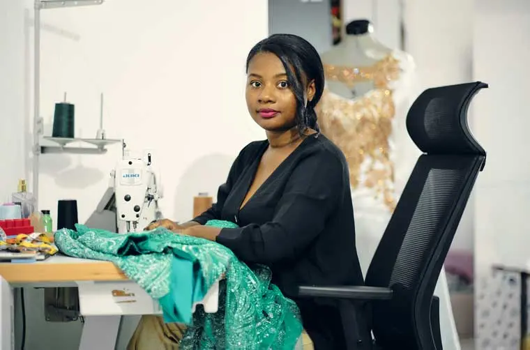 Entrepreneuse financée par l'Adie utilisant sa machine à coudre pour créer un vêtement