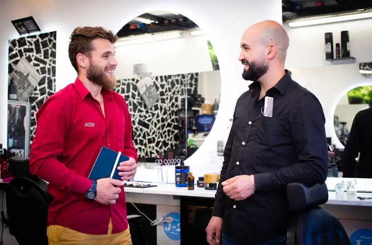 Entrepreneur ayant un statut SAS discutant avec son conseiller Adie dans son salon de coiffure