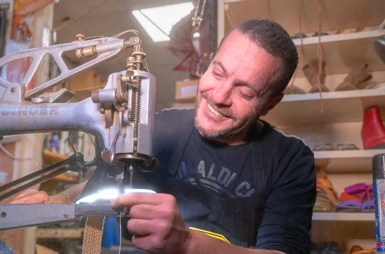 Cordonnier financé par l'Adie travaillant sur sa machine