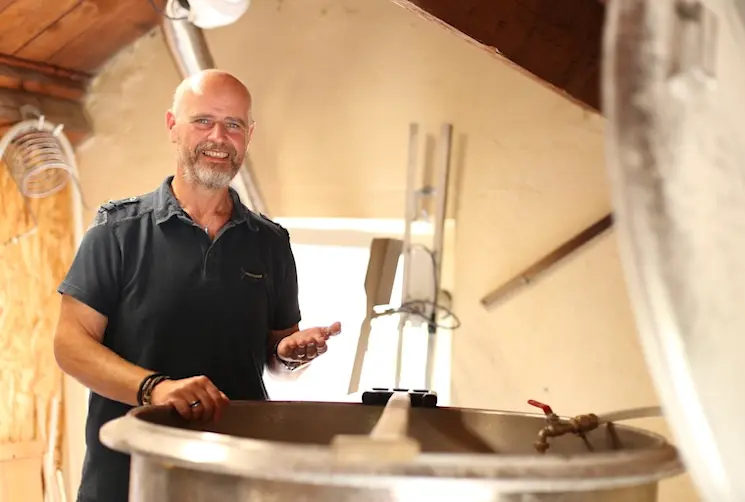 Gérant d'une microbrasserie financé par l'Adie devant l'une de ses machines