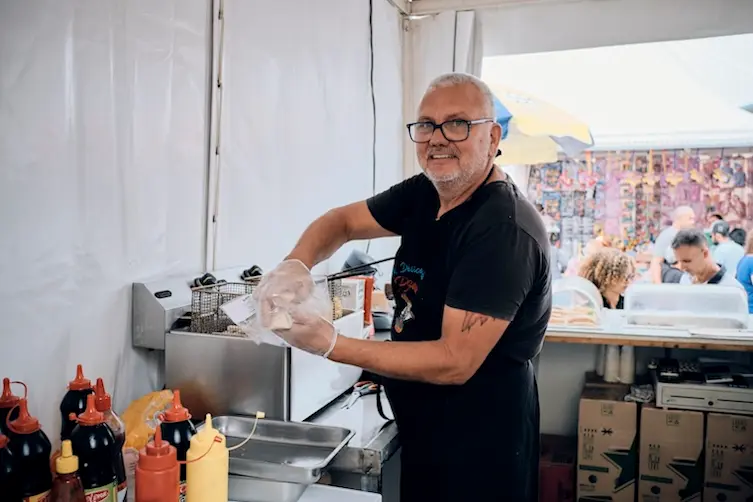 Entrepreneur financé par l'Adie préparant un plat de restauration rapide à ses clients