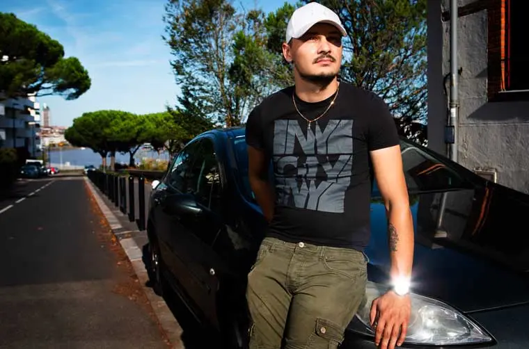 Entrepreneur financé par l'Adie appuyé sur sa voiture