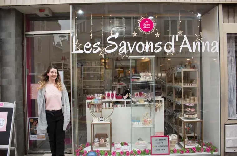 Entrepreneuse financée par l'Adie devant son commerce