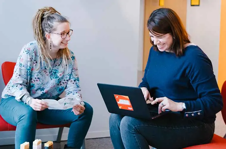 Deux femmes sourient lors d'un rendez-vous d'accompagnement chez l'Adie.