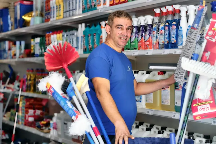 Gérant d'une entreprise de nettoyage de bureaux financé par l'Adie achetant ses produits nettoyants