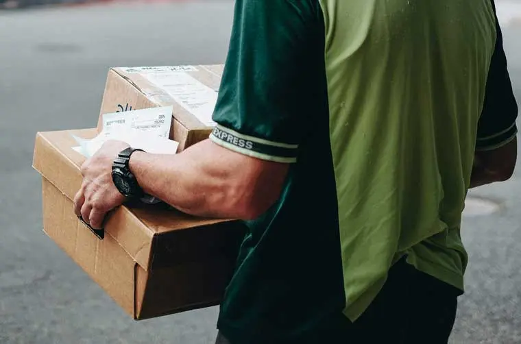 Entrepreneur livreur financé par l'Adie portant des colis
