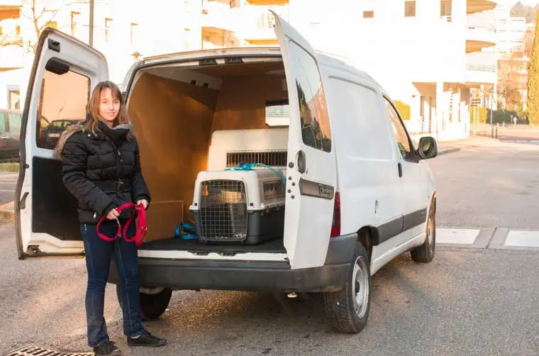 Entrepreneuse financée par l'Adie à côté de son véhicule d'occasion