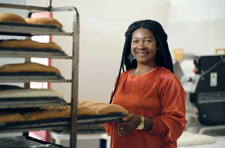 Entrepreneuse boulangère financée par l'Adie rangeant ses pains