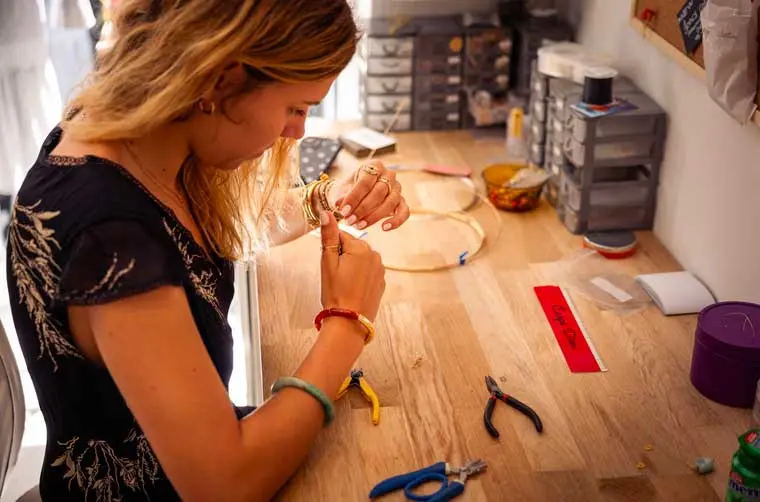 Entrepreneuse financée par l'Adie travaillant une tige de fer dorée avec ses pinces